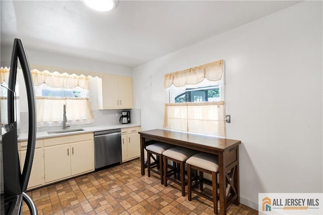 235 Brook Ave, North Plainfield, NJ 07060 - kitchen featuring stainless steel dishwasher, freestanding refrigerator, light countertops, cream cabinetry, and brick patterned floors