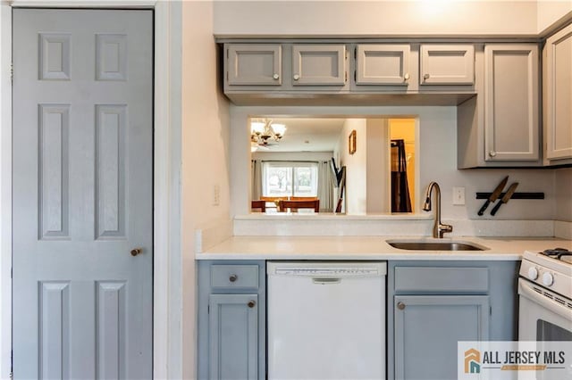 kitchen featuring gray cabinetry, a sink, white appliances, and light countertops