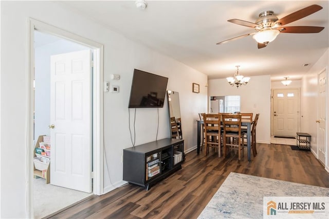 dining area with dark wood-type flooring, baseboards, and ceiling fan with notable chandelier