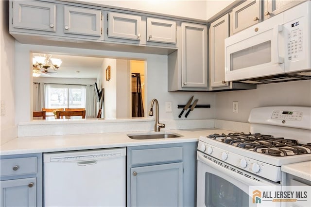kitchen featuring light countertops, an inviting chandelier, a sink, and white appliances
