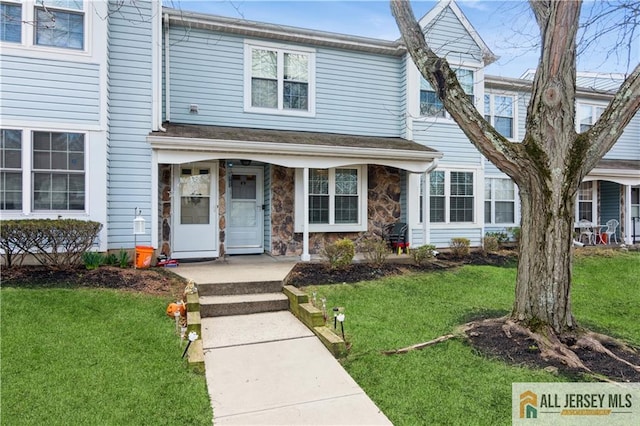 townhome / multi-family property with stone siding, a front yard, and covered porch