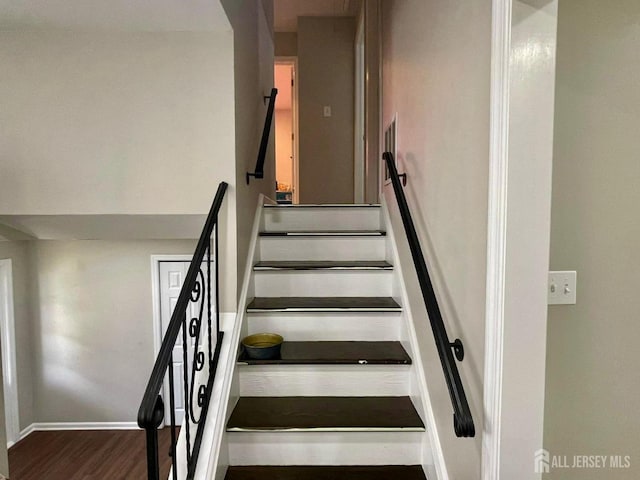 staircase featuring wood finished floors and baseboards