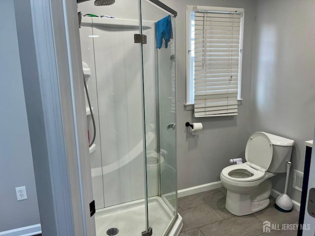 bathroom featuring baseboards, toilet, tile patterned flooring, and a stall shower