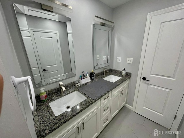 bathroom with tile patterned floors, baseboards, a sink, and double vanity