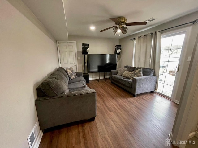 living area featuring wood finished floors, visible vents, a ceiling fan, and baseboards