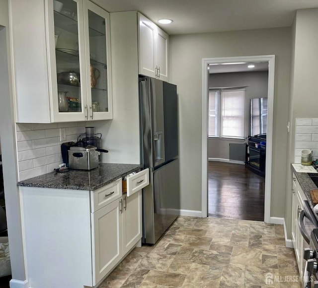 kitchen featuring white cabinets, baseboards, decorative backsplash, and refrigerator with ice dispenser