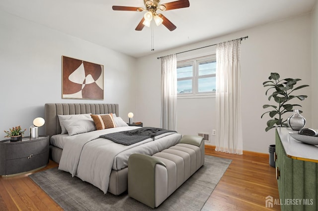 bedroom featuring light wood finished floors, visible vents, ceiling fan, and baseboards