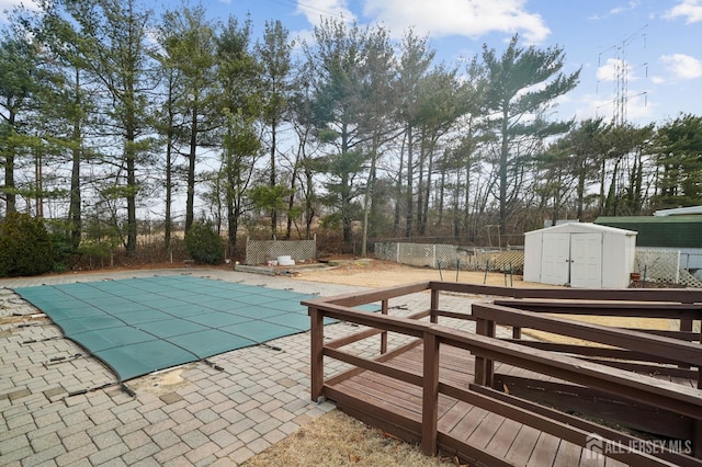 view of swimming pool with a covered pool, fence, a shed, an outdoor structure, and a patio