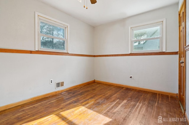 spare room featuring visible vents, baseboards, ceiling fan, and hardwood / wood-style flooring