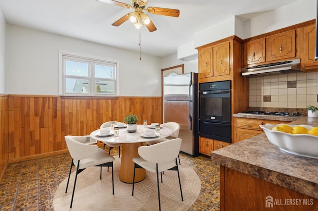 kitchen with under cabinet range hood, a wainscoted wall, appliances with stainless steel finishes, and a warming drawer