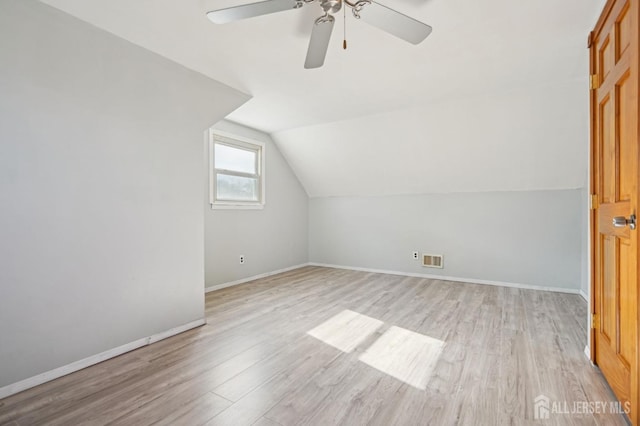 bonus room featuring light wood-type flooring, visible vents, baseboards, and lofted ceiling