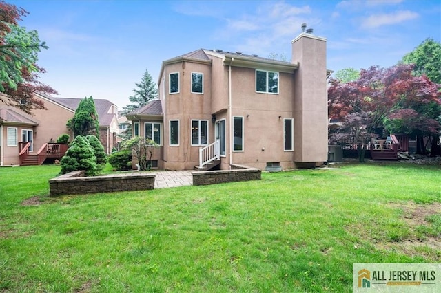 124 Kingsland Cir S, Brunswick, NJ 08852 - back of house with a chimney, a yard, a wooden deck, stucco siding, and a patio area