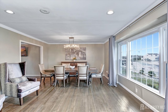 dining area with wood-type flooring, a notable chandelier, and ornamental molding