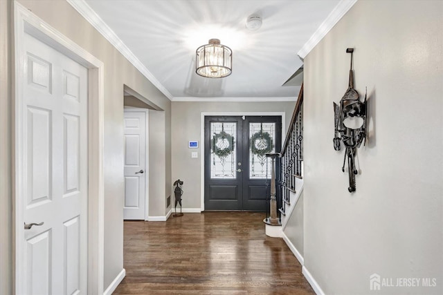 entrance foyer featuring dark wood-type flooring, a chandelier, ornamental molding, and french doors