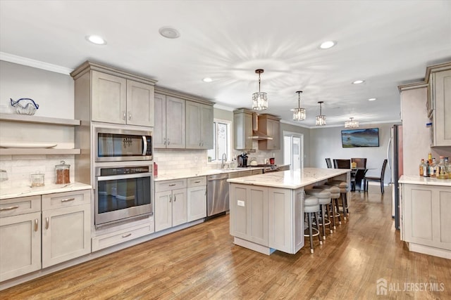 kitchen featuring hanging light fixtures, appliances with stainless steel finishes, backsplash, a kitchen bar, and a kitchen island