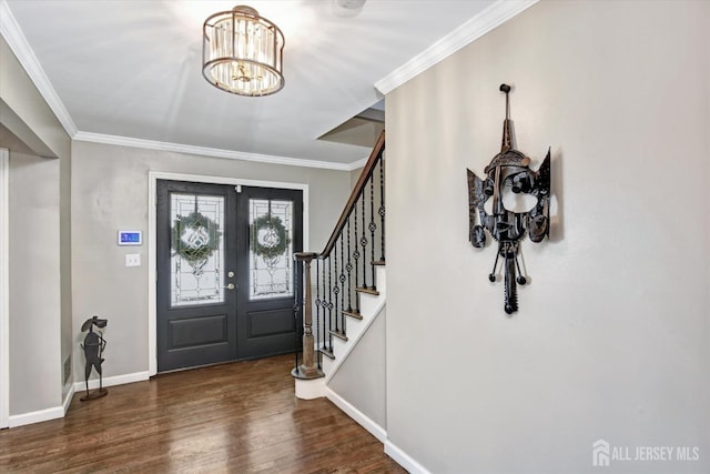 foyer featuring dark wood-type flooring, french doors, crown molding, and a notable chandelier