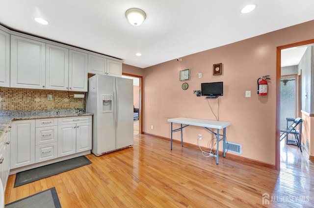 77 Manhattan Ave, Avenel, NJ 07001 - kitchen with white refrigerator with ice dispenser, light wood finished floors, tasteful backsplash, light stone countertops, and white cabinetry