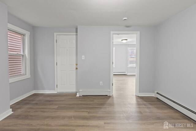 spare room featuring wood-type flooring and a baseboard radiator