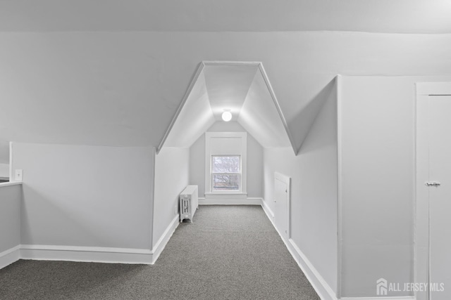 bonus room with radiator, dark colored carpet, and lofted ceiling