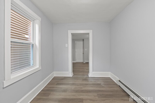 unfurnished room featuring hardwood / wood-style floors and a baseboard radiator