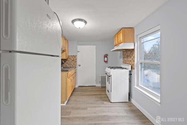 kitchen featuring decorative backsplash, white appliances, light hardwood / wood-style flooring, light brown cabinetry, and radiator heating unit