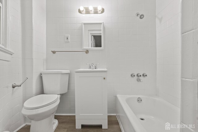 bathroom with toilet, a bathtub, hardwood / wood-style flooring, and vanity