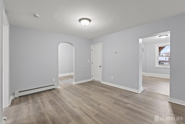 unfurnished room featuring light wood-type flooring and baseboard heating