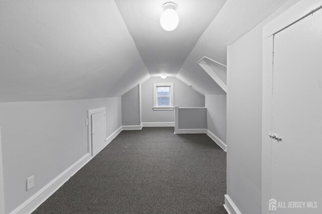 additional living space featuring vaulted ceiling and dark carpet