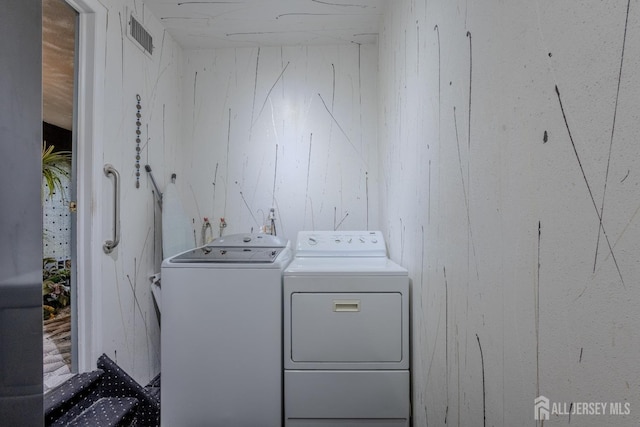 laundry room with washing machine and clothes dryer and wood walls