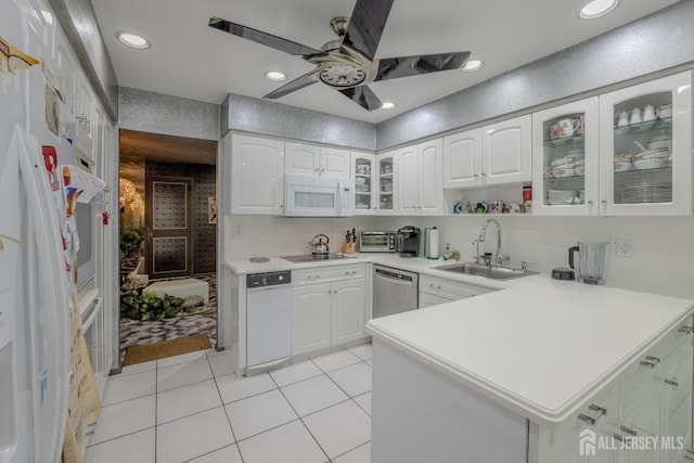 kitchen featuring a sink, white appliances, a peninsula, glass insert cabinets, and light countertops