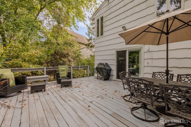 wooden deck featuring a grill and outdoor dining space