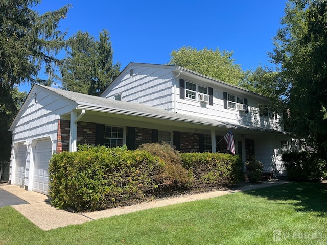 view of front of house featuring a front yard, an attached garage, brick siding, and driveway