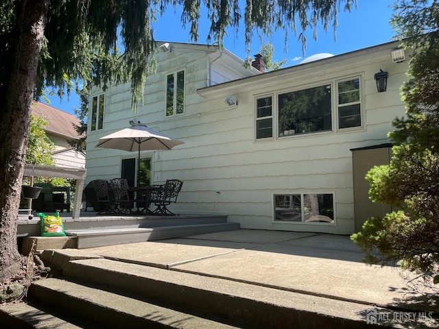 back of house with a patio area and a chimney