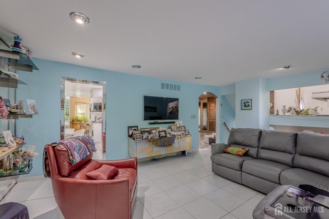 living area featuring arched walkways, light tile patterned flooring, and recessed lighting