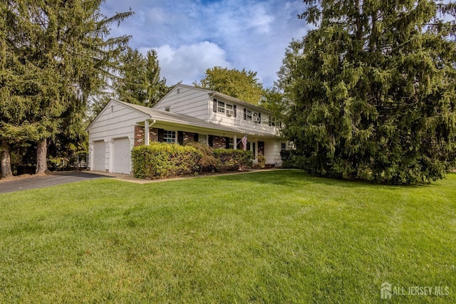 view of front of home with driveway, a front yard, a garage, and brick siding