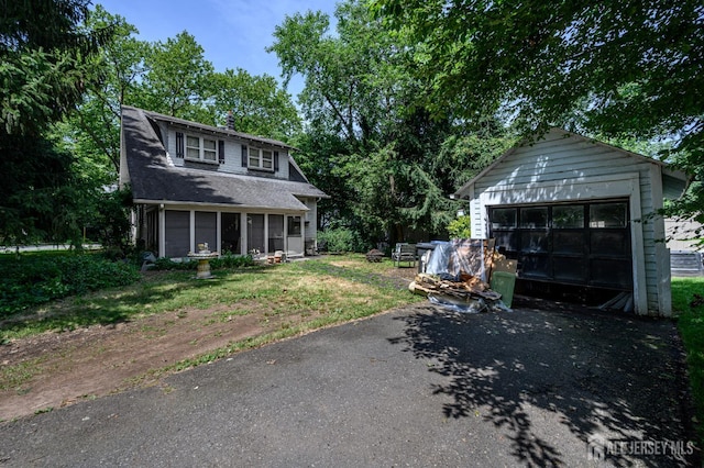 570 Main St, Metuchen, NJ 08840 - view of front of property with asphalt driveway, a garage, a sunroom, and an outbuilding