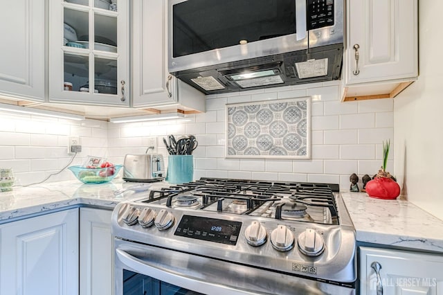 16 Jeanette Ct Unit 293, Jamesburg, NJ 08831 - kitchen featuring appliances with stainless steel finishes, glass insert cabinets, backsplash, white cabinetry, and light stone counters