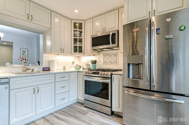 16 Jeanette Ct Unit 293, Jamesburg, NJ 08831 - kitchen with stainless steel appliances, light wood-type flooring, glass insert cabinets, tasteful backsplash, and white cabinets