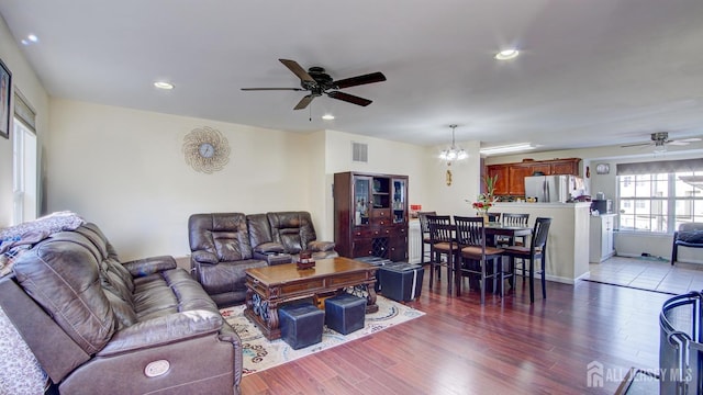 living room with dark hardwood / wood-style floors and ceiling fan with notable chandelier