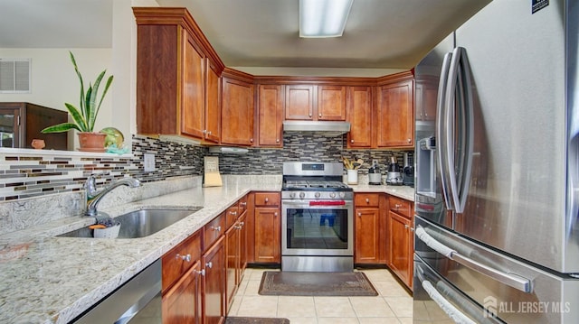 kitchen featuring backsplash, sink, light stone countertops, light tile patterned floors, and stainless steel appliances