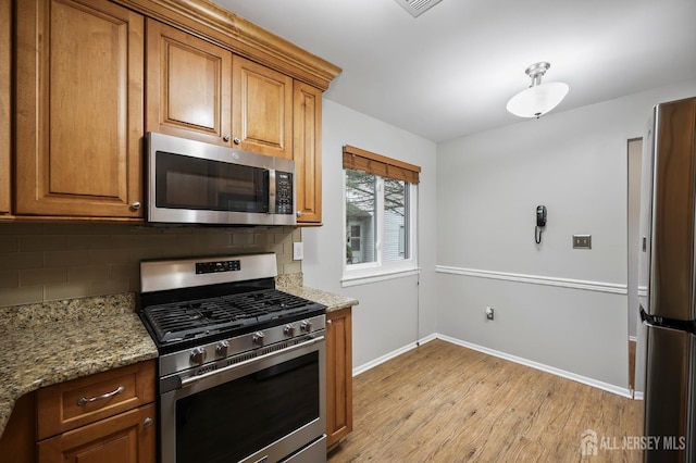 70 Lexington Cir, Old Bridge, NJ 07747 - kitchen with appliances with stainless steel finishes, light wood-type flooring, tasteful backsplash, and brown cabinets