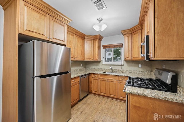 70 Lexington Cir, Old Bridge, NJ 07747 - kitchen with stainless steel appliances, light wood-style floors, backsplash, light stone counters, and brown cabinetry