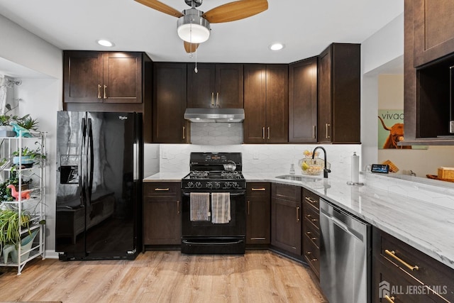 kitchen featuring sink, light hardwood / wood-style flooring, light stone counters, tasteful backsplash, and black appliances