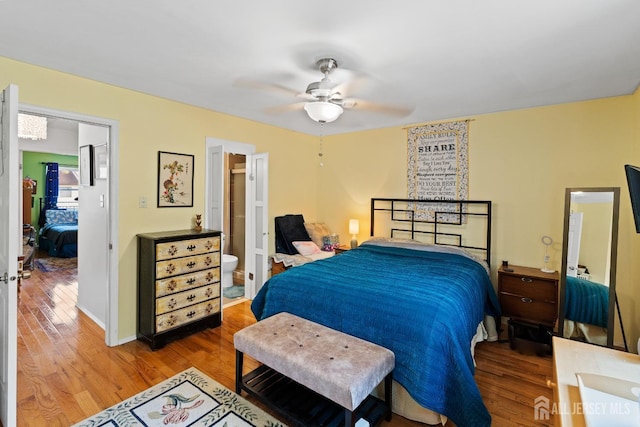 bedroom with ceiling fan, connected bathroom, and hardwood / wood-style floors