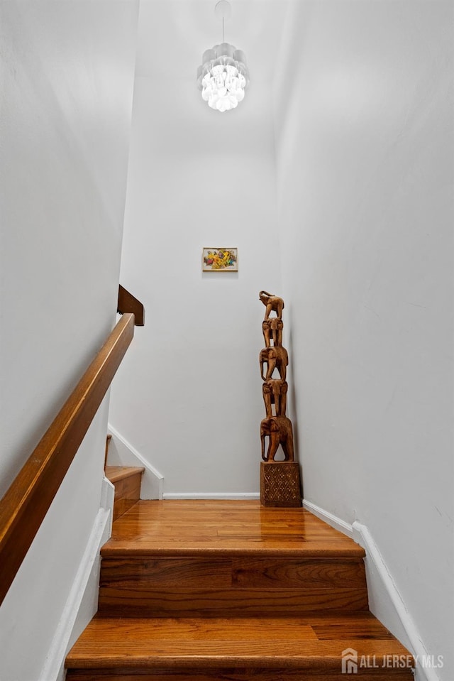 staircase with a chandelier and hardwood / wood-style floors