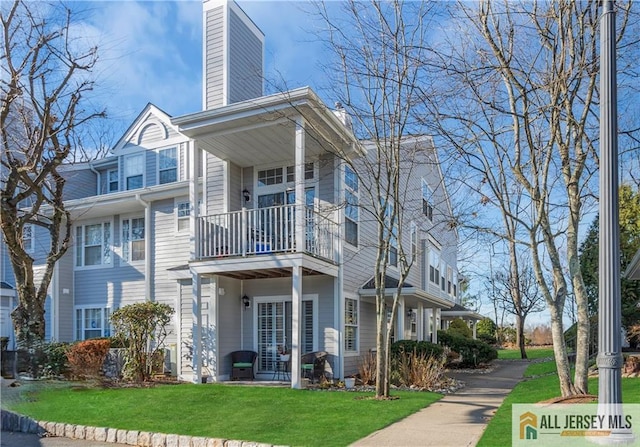 view of home's exterior with french doors, a lawn, a chimney, and a balcony