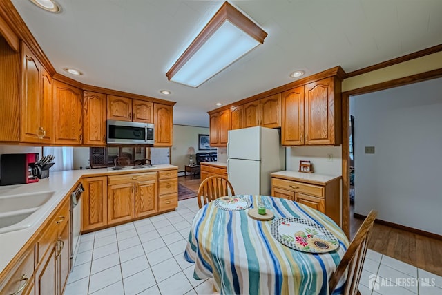 kitchen with light tile patterned floors, appliances with stainless steel finishes, sink, and crown molding