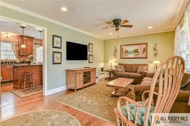 living room with ceiling fan, baseboards, ornamental molding, and light wood finished floors