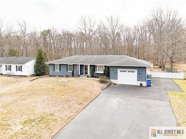 ranch-style home with driveway, a front lawn, fence, an attached garage, and a shingled roof