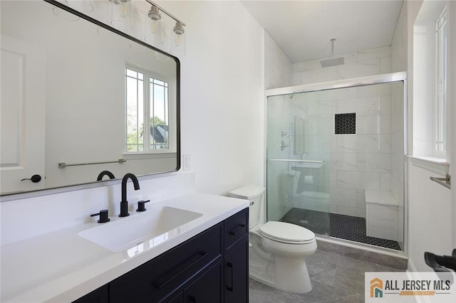 bathroom featuring vanity, a shower with shower door, and toilet